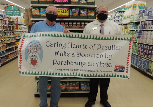 Banner held by the president of Carign Hearts of Peculiar and the Manager of the Peculiar Cosentino's Price Chopper. The banner reads: Caring Hearts of Peculiar. Make a Donation by Purchasing an Angel. Caring Hearts is a 501(c)(3) Tax Deductible Organization.
